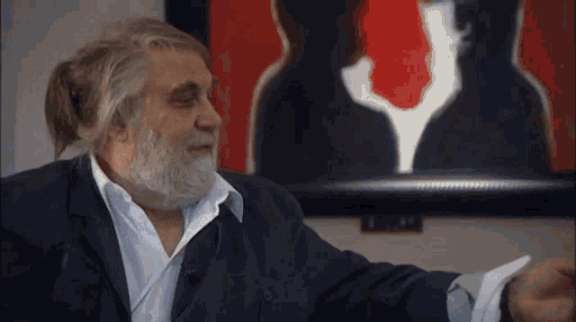 a man with a beard is standing in front of a picture