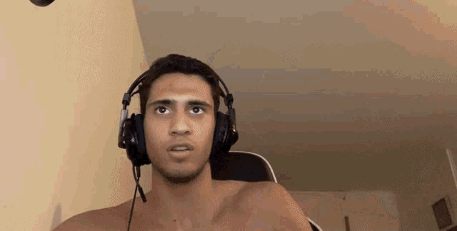 a man without a shirt is wearing headphones with a microphone