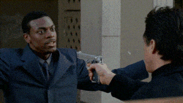 a man in a suit is pointing a gun at another man in a tie