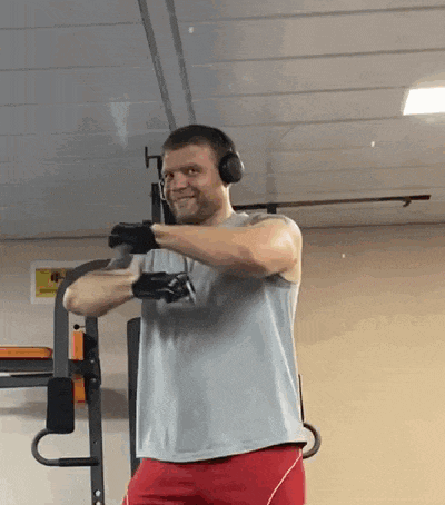 a man wearing headphones and boxing gloves is doing exercises in a gym