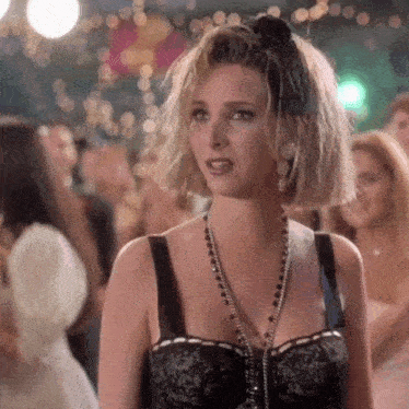 a woman wearing a black bra and necklace is standing in a crowd .