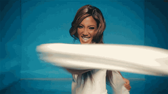 a woman in a white shirt is smiling while holding a white object