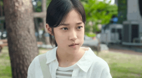 a young girl in a white shirt and striped shirt is making a funny face .
