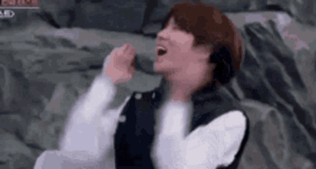 a man wearing headphones is singing into a microphone while laughing .