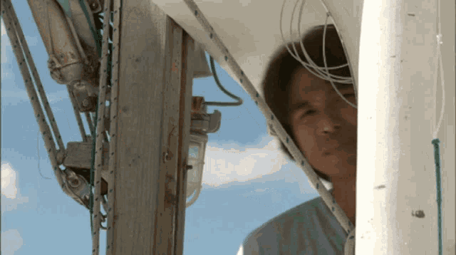 a man looks out from behind a white pole