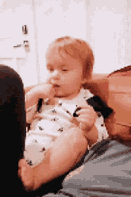 a baby is sitting on a couch with a person holding it .
