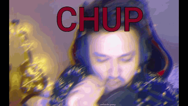 a blurred image of a man with the word chup written in red