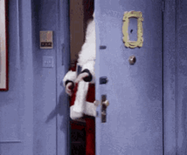 a man in a santa suit is standing in a doorway