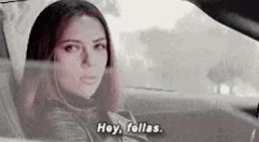 a black and white photo of a woman sitting in a car talking .