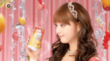 a woman with a tiara on her head is holding a can of pringles .