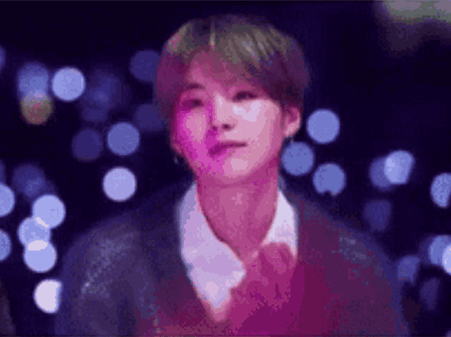 a close up of a person 's face in a blurry photo with purple lights in the background .