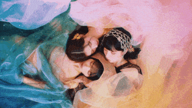 three women are laying on top of each other with their heads on each other 's shoulders