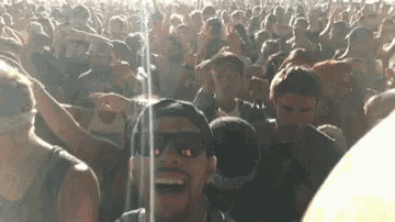 a man is taking a selfie in front of a crowd at a concert .