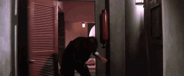 a man standing in a hallway with a fire extinguisher in the background