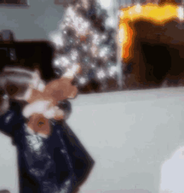 a blurred image of a person holding a teddy bear in front of a christmas tree