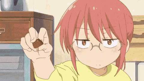 a girl with red hair and glasses is holding a chocolate bar in her hand .