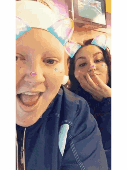 a woman wearing a cat ear headband is laughing next to another woman