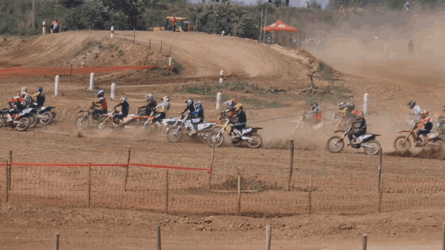 a group of dirt bike riders are on a dirt track