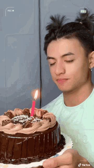 a man is holding a cake with a lit candle on it