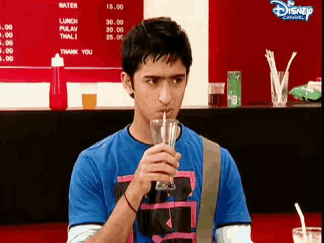 a man drinking through a straw in front of a menu that says disney channel