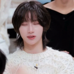 a young man wearing a white sweater with his eyes closed