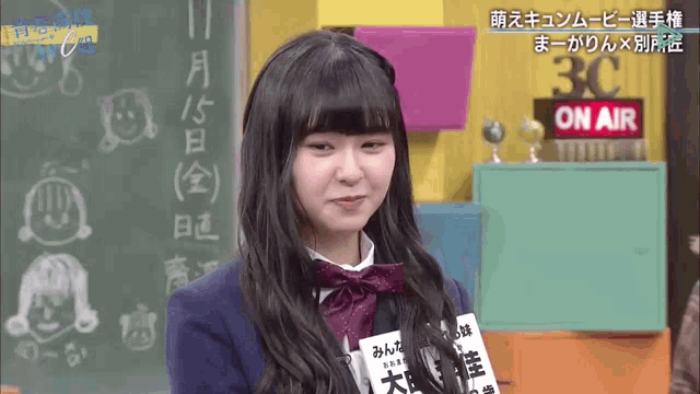 a girl stands in front of a sign that says 3c on air