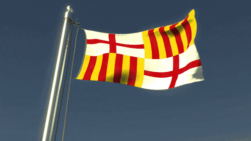 a red white and yellow flag is waving in the wind against a blue sky