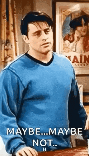 a man in a blue sweater is standing in front of a poster that says maybe ... maybe not .