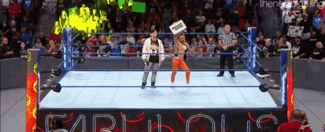a man and a woman are standing in a wrestling ring in front of a sign that says capitol city