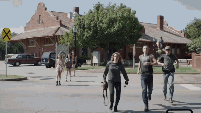 a group of people are running down a street in front of a building that has a sign that says railroad
