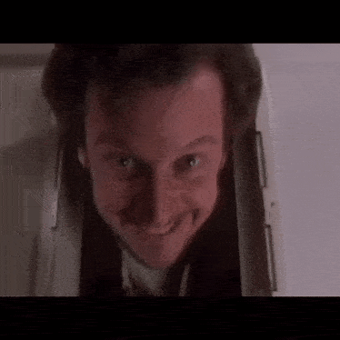 a close up of a man 's face looking out of a doorway and smiling .