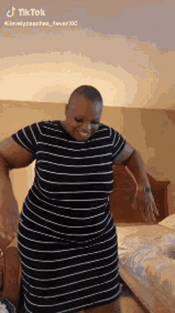 a woman in a black and white striped dress is dancing in a bedroom .
