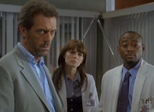 a man in a suit talks to a woman and a man in a white coat