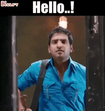a man in a blue shirt is standing in front of a door and saying `` hello '' .