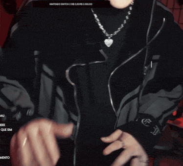 a person wearing a heart shaped necklace and a nintendo switch 2 sweatshirt