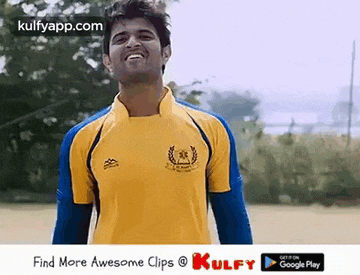 a man in a yellow and blue shirt is smiling and looking at the camera .