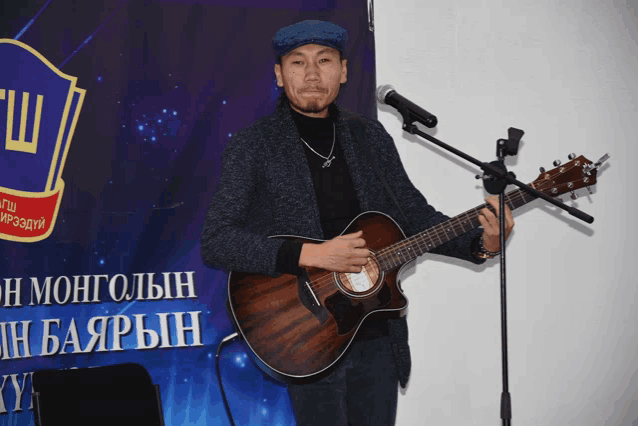 a man playing an acoustic guitar in front of a sign that says " mongolin "