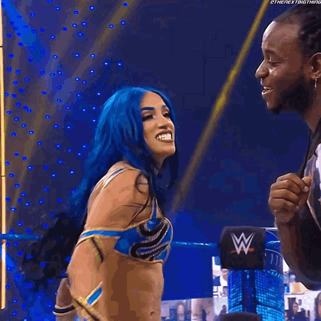 a woman with blue hair is standing next to a man in a ring .