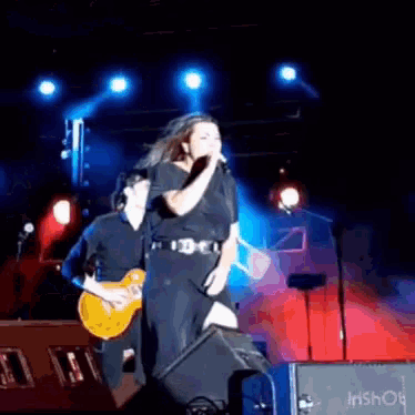 a woman singing into a microphone while a man plays guitar