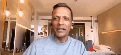 a man is talking on a video call while wearing headphones in a hotel room .