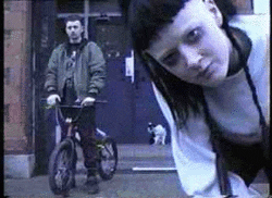 a man is riding a bike next to a woman who is looking at the camera .