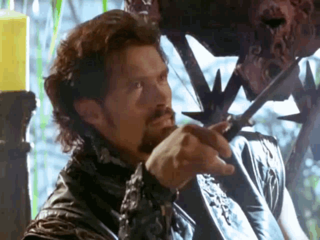a man with a beard is holding a sword in front of a candle holder .