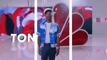a man in a blue shirt is standing in front of a wall with the word ton written on it