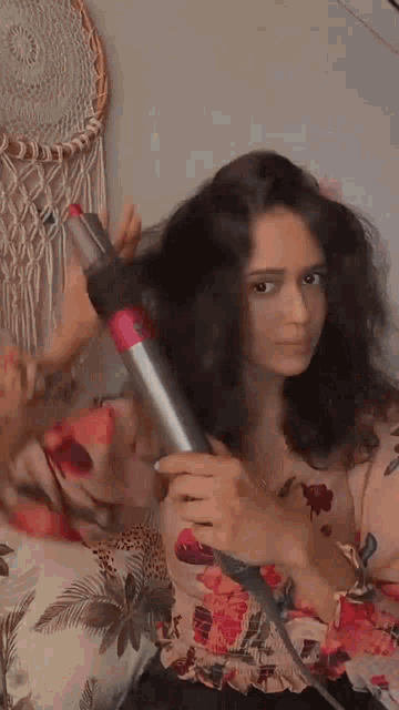 a woman is blow drying her hair with a dyson hair dryer .