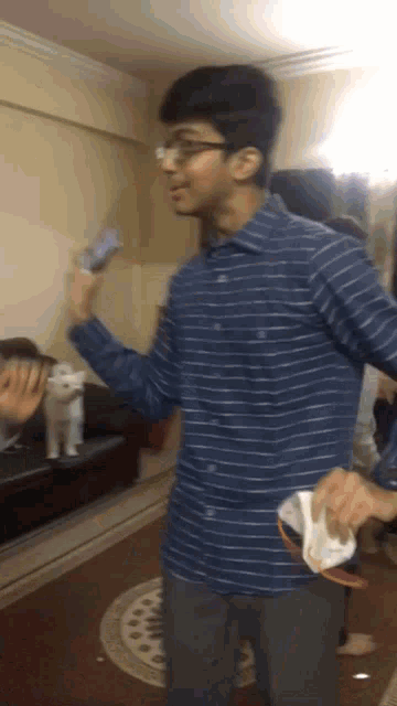 a man in a blue striped shirt holds a remote control