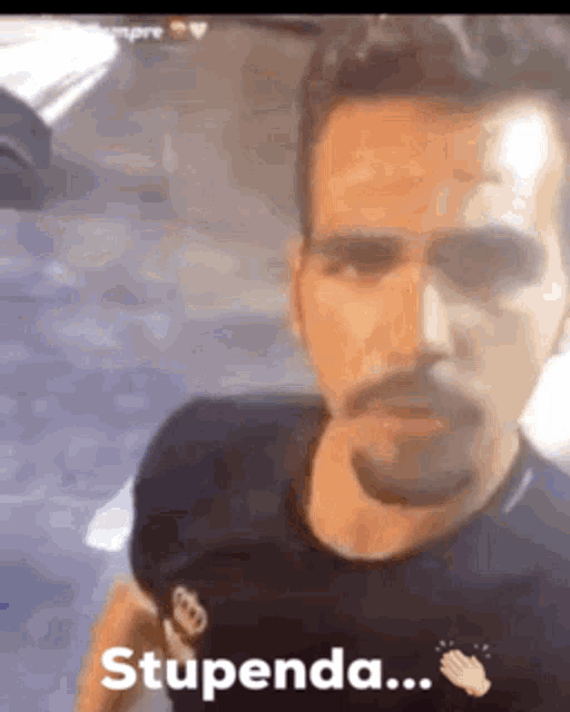 a man with a beard and mustache is wearing a black shirt that says stupenda