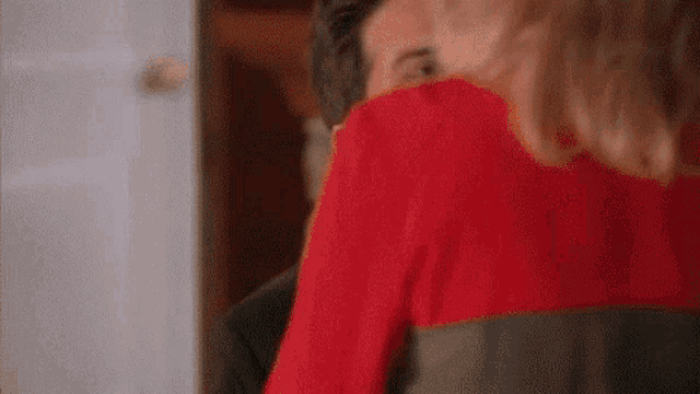 a man and a woman are kissing in a room . the woman is wearing a red dress .