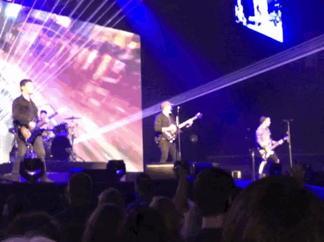 a group of people playing instruments on a stage with a large screen behind them that says ' i love you '