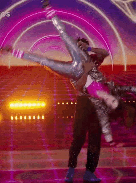 a man is holding a woman up in the air on a stage with a purple background