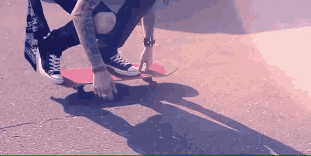 a person kneeling down on a red skateboard with a bandana around their waist